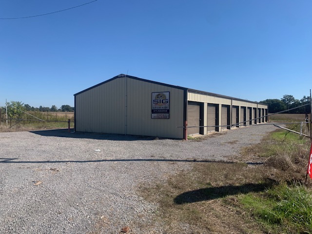 SIG LLC storage building with roll-up doors and an SIG Storage sign on a gravel lot